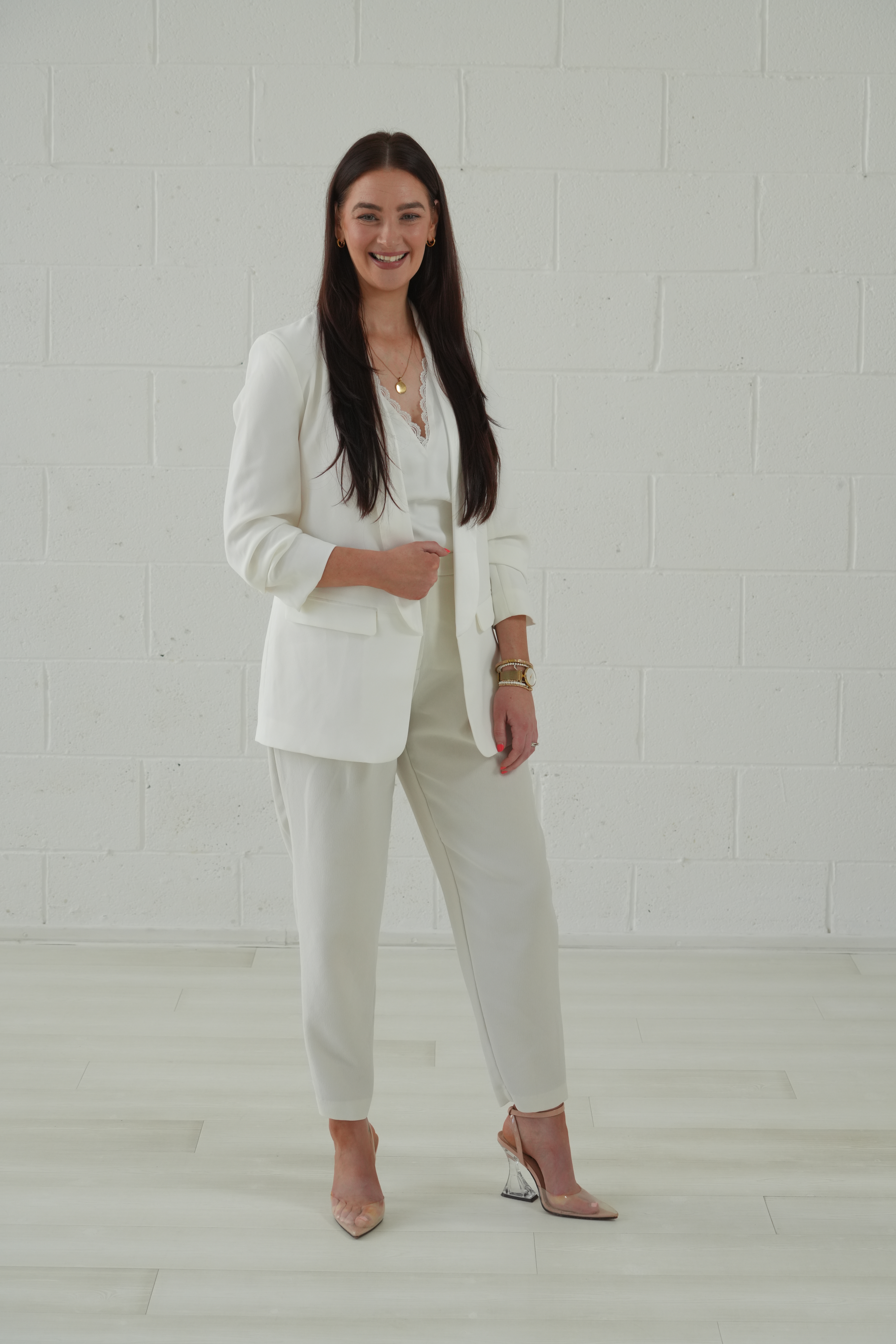Rose Cottage Property Staging founder in an all-white suit against a white brick wall